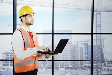 Arabian engineer with a laptop near the window