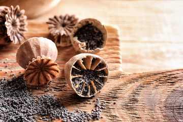 Board with poppy heads and seeds on table, closeup