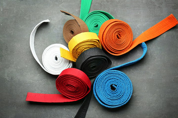 Colorful karate belts on grey background