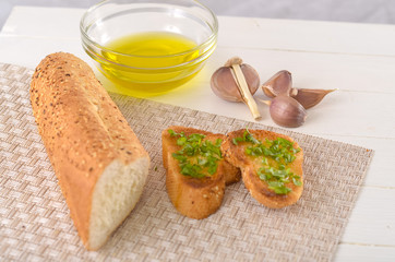 Fried bread with olive oil, garlic and herbs on a wooden table. Rustic style.