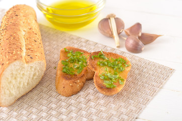 Fried bread with olive oil, garlic and herbs on a wooden table. Rustic style.