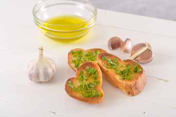 Fried bread with olive oil, garlic and herbs on a wooden table. Rustic style.