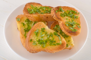 Fried bread with olive oil, garlic and herbs on a wooden table. Rustic style.