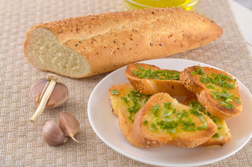 Fried bread with olive oil, garlic and herbs on a wooden table. Rustic style.