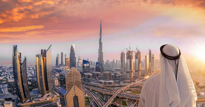 Arabian man watching cityscape of Dubai with modern futuristic architecture in United Arab Emirates.