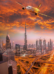 Fototapeta premium Airplane is flying over Dubai against colorful sunset in United Arab Emirates
