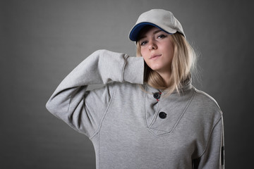 Young beautiful blonde woman in gray sport wear against gray background.