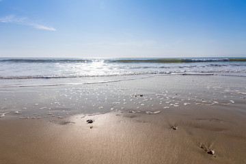 sun shining on waves on beach