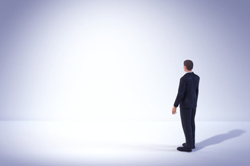 Fototapeta na wymiar toy miniature businessman figure standing and looking at empty white lit space, concept background