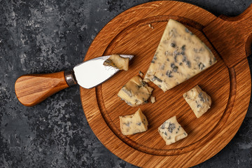 Pieces of blue cheese on wooden serving board.