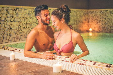 Happy couple relaxing in a warm pool at hotel spa