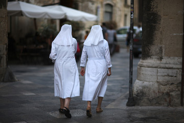 Two nuns are walking along the street of the old city. Lecce, Italy