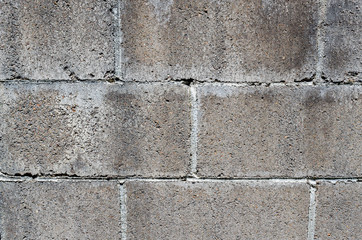 Textured cement block building surface wall.  Abstract rough background or backdrop.  Detail in this unpainted gray cinder block surface.