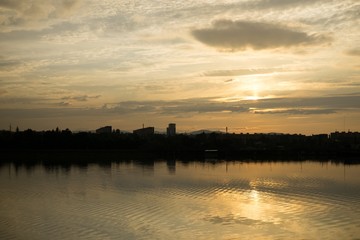 Colorful sunset on the lake with reflections of hills, trees and buildings. Slovakia