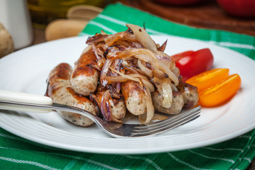 Fried Fried white sausages with onion on the plate.white sausages in a cast iron skillet.