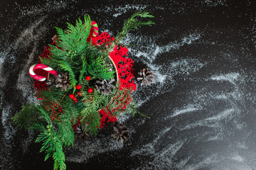 Traditional christmas composition with fir tree branch,candy,berry,strobile on black background.