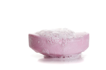 A bar of soap with soap bubbles on white background