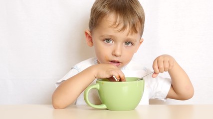 boy eats food with a spoon sitting at the table