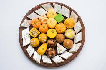 Stock photo of Indian sweets served in silver or wooden plate. variety of Peda, burfi, laddu in...