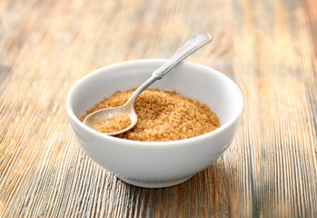 Bowl and spoon with cinnamon sugar on wooden table