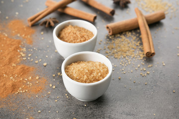 Bowls with cinnamon sugar on grey background
