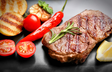 Tasty grilled steak on dark background