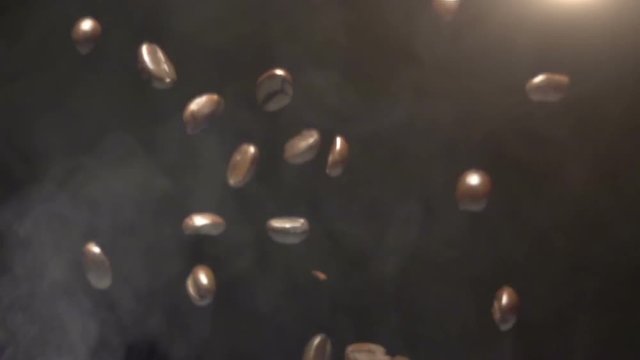 Roasted coffee beans falling. Slow motion at 960 fps on black background and steam below. , 960 fps