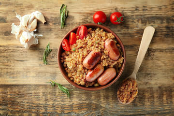 Bowl with boiled lentils and sausages on table
