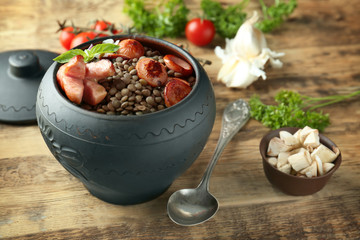 Pot with black lentils and sausages on table