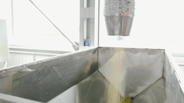 Wheat grains pouring down from metal tube, making a huge pile