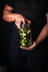 Fermented pickled cucumbers salt natural glass mason jars hands person canning concept