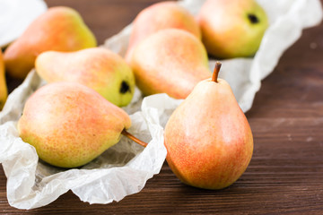 Ripe pears in a paper on a wooden table
