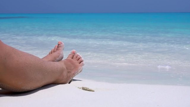 Female toe on sandy beach in caribbean sea waves. Tropical vacation 