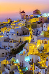 Oia town, Santorini island, Greece at sunset. Traditional and famous white houses and churches  with blue domes over the Caldera, Aegean sea.