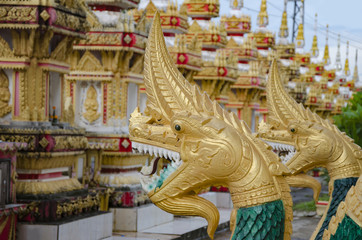 Fototapeta na wymiar Golden dragons and stupas of a buddhist temple near Pha that luang in Vientiane, Laos