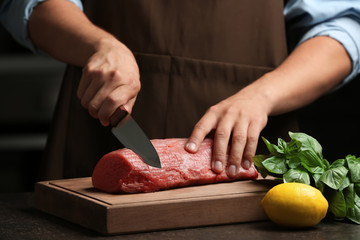 Chef cutting fresh raw meat on wooden board