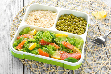 Lunch box with delicious salmon salad and garnish on table