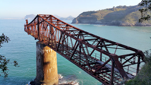 Bridge to nowhere. Abandoned overpass for loading ore from an old mine on the seashore. View from above, against the background of the sea. Miono, Cantabria, North spain.