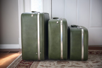 Set of vintage luggage waiting by a front door.