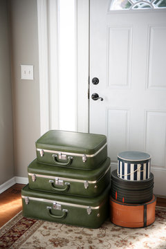 Set of vintage luggage and hatboxes waiting by the front door.