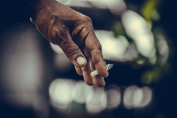 Close up of man hand with cigarette in his fingers on green background. vintage tone.