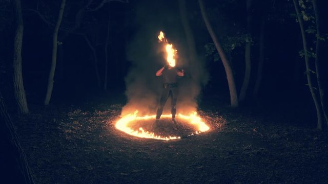 Fire performance in the night forest by the gothic girl