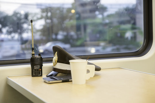 Hat of a police train Placed on the table by the train window. With radio and coffee mugs