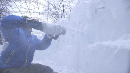 View of sculptor carving ice. Movement. Cut ice with a chainsaw. Cut and make snow sculpture....