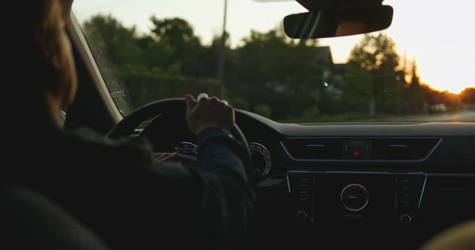 Man Driving a Car at Dusk. SLOW MOTION 4K DCi. Male Hand on steering wheel close up. Beautiful Road in blurred background.