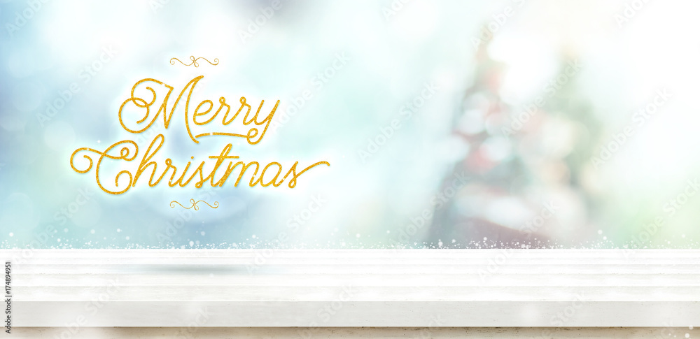 Poster merry christmas gold glitter on white wooden table with abstract muted blur christmas tree and snow 