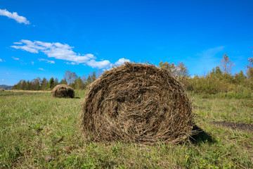 haystack on farmland with blue cloudy  sky