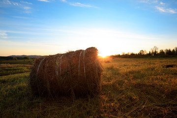 haystack on farmland with blue cloudy sunset sky