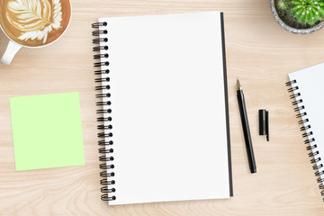Blank notebook page is on top of wood office desk table with supplies. Top view, flat lay.