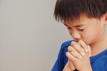 asian boy praying with eyes closed
